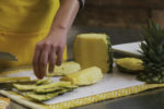 A produce clerk cuts up a pineapple