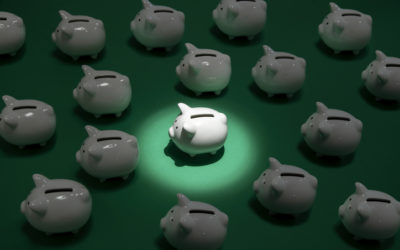 many small white piggy banks on green surface one piggy bank being spot lit