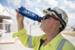 Man in hardhat outside drinks from a UFCW water bottle