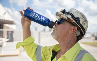 Man in hardhat outside drinks from a UFCW water bottle