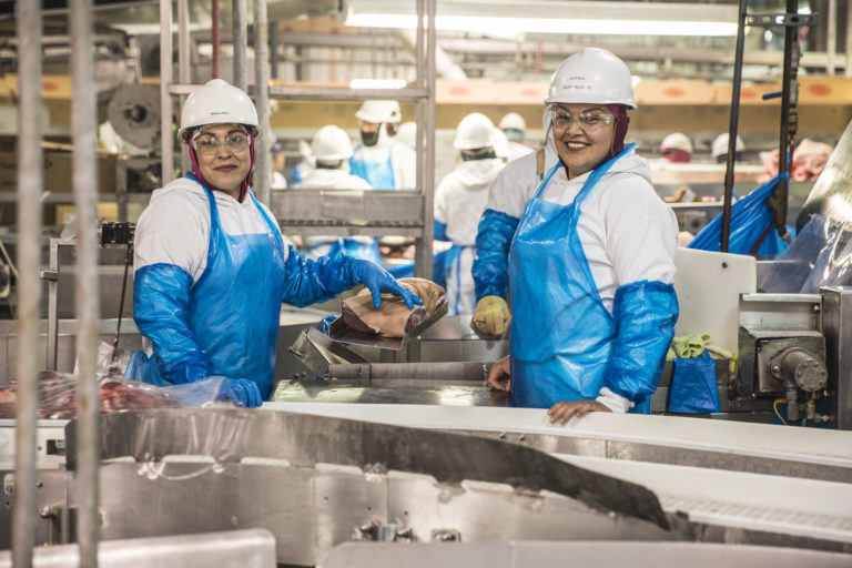 Two women who are UFCW 1149 members in a meatpacking plant