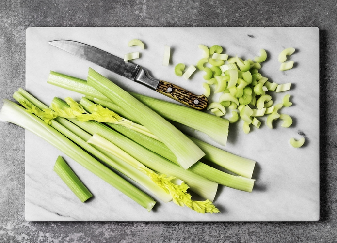 Celery stalks on white cutting board
