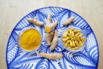 High angle view of turmeric root, powder and pills on plate