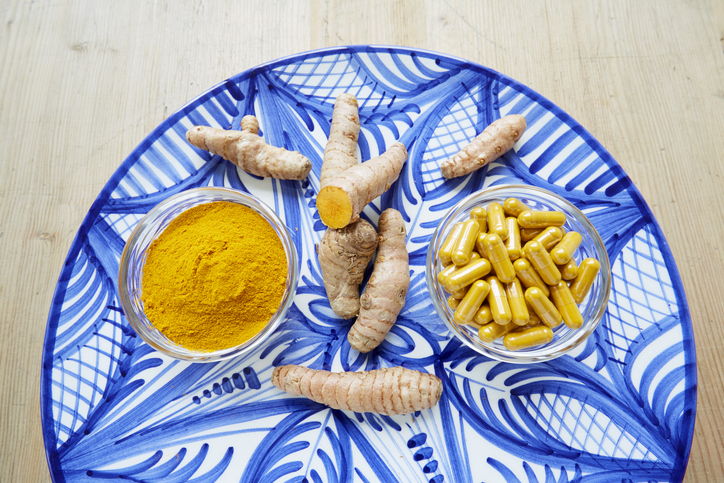 High angle view of turmeric root, powder and pills on plate