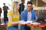 Cropped shot of two young students working on a laptop together while waiting for class outside of a school