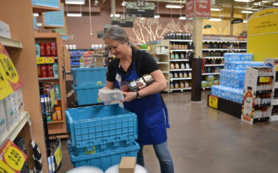 Woman at Kroger stocks shelves from blue bins