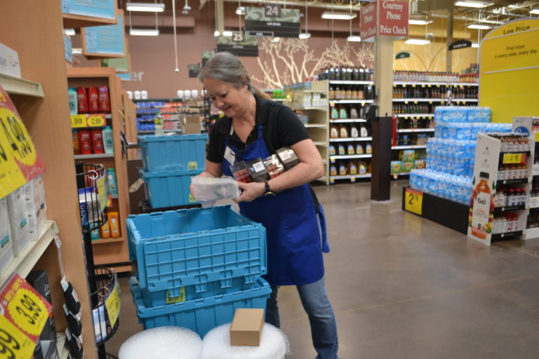 Woman at Kroger stocks shelves from blue bins