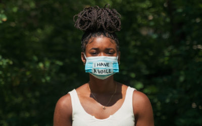 A young Black woman wears a face mask during global pandemic that says 