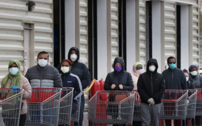 Customers wear face masks to prevent the spread of the novel coronavirus as they line up to enter a store