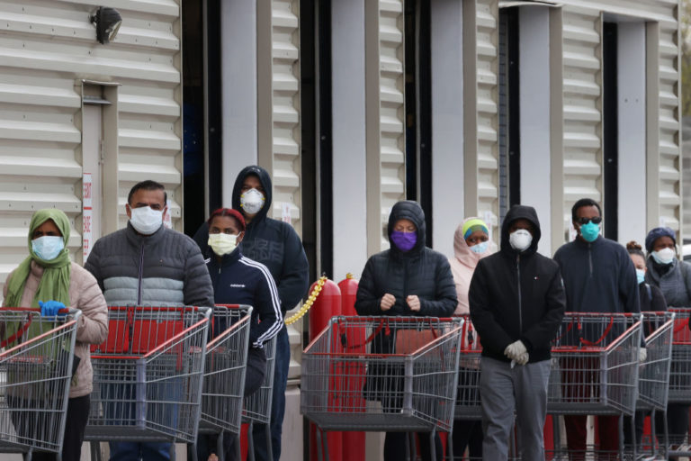 Customers wear face masks to prevent the spread of the novel coronavirus as they line up to enter a store