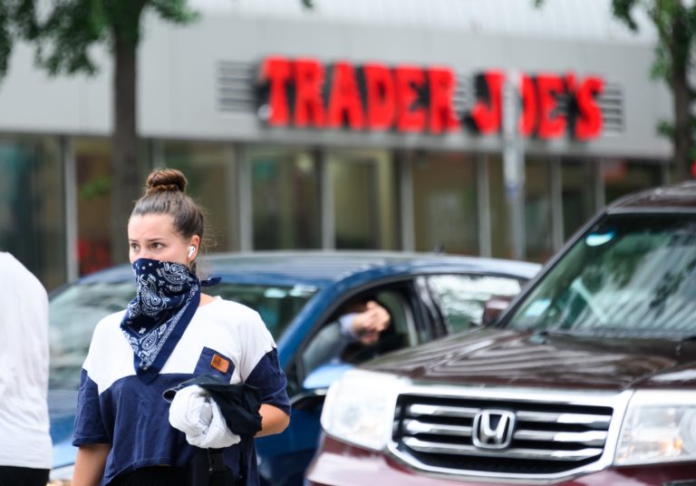 A person wears a bandana face covering outside of Trader Joe's